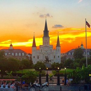 a castle with a clock on the tower of the city with Jackson Square in the background