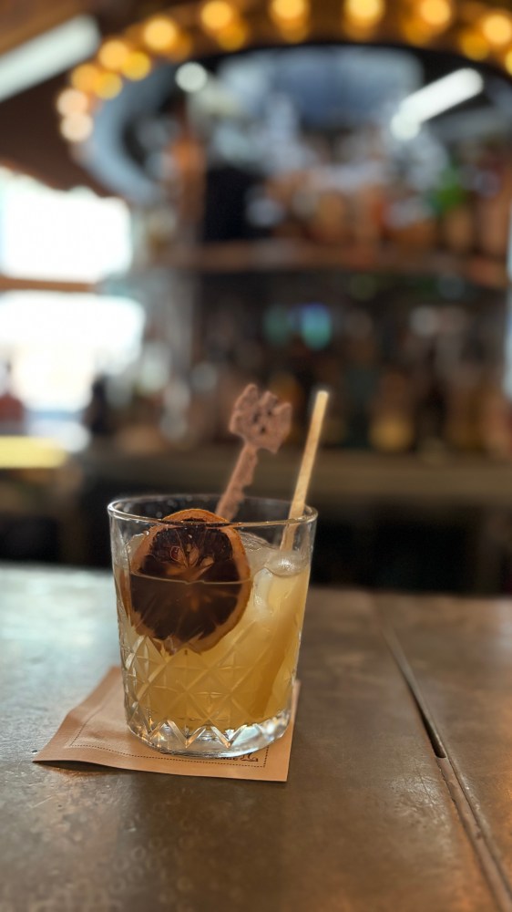 Cocktail glass with dried citrus garnish on bar counter.