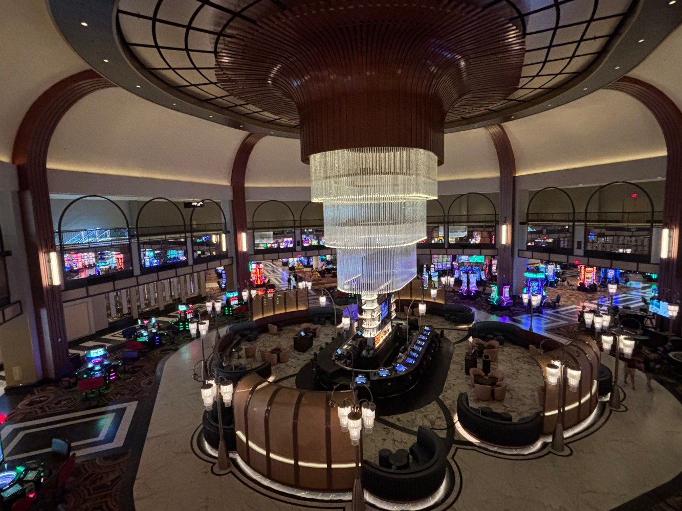 Grand casino interior with a large chandelier, gaming tables, and machines.